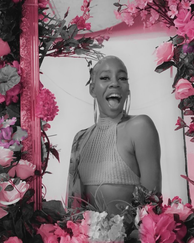 Fatima M., founder of Tend Collective, surrounded by pink florals